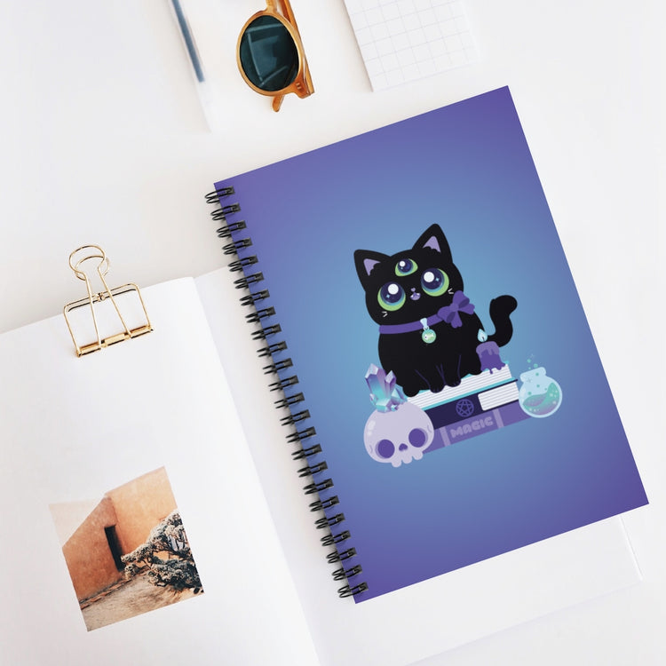spiral notebook journal with a 3-eyed black cat witch with a spooky crystal skull, a magic potion, and a melting candle sitting on a stack of spellbooks